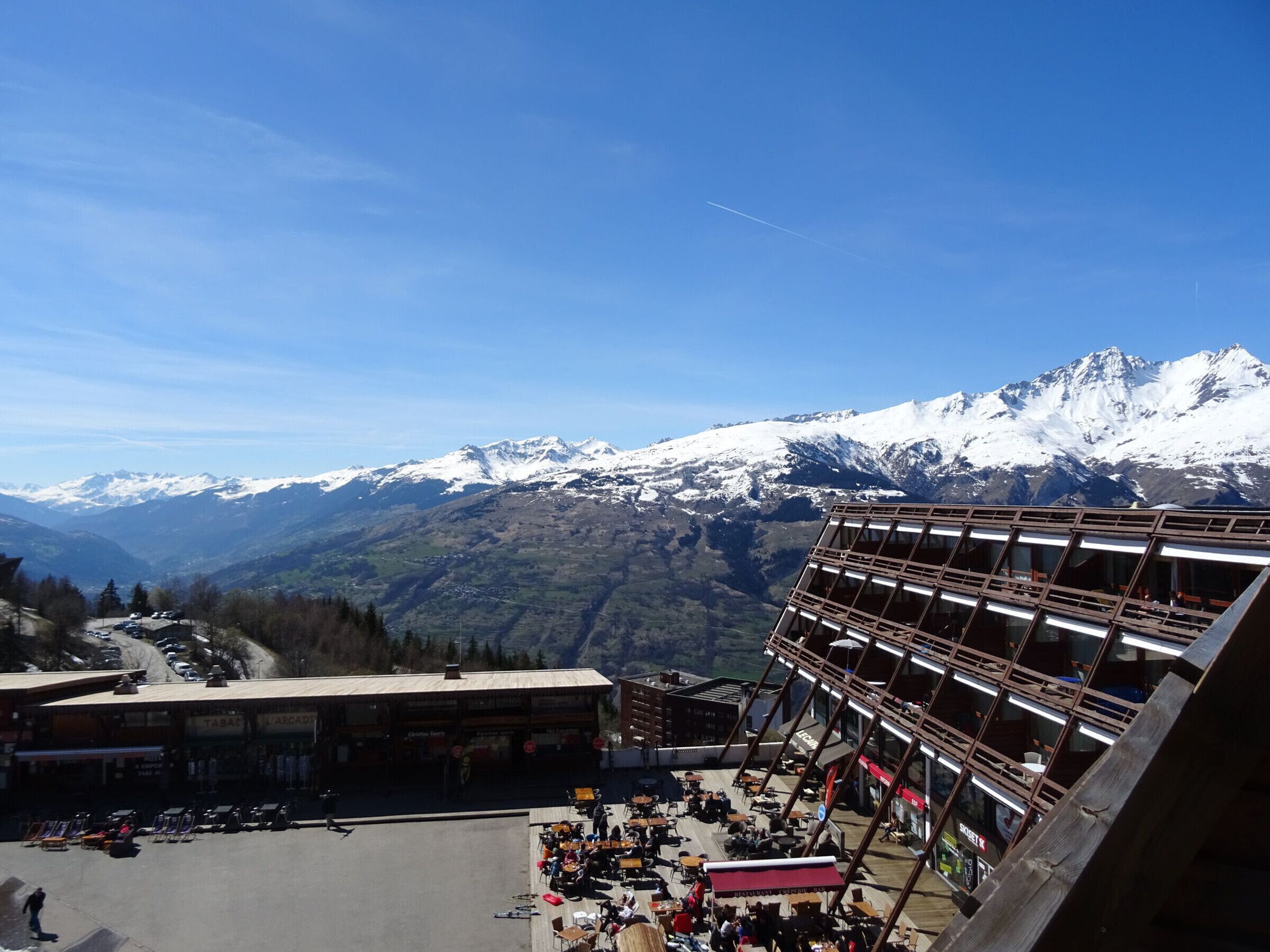 A ski resort with a restaurant on the upper level, offering views of snow-covered mountains.