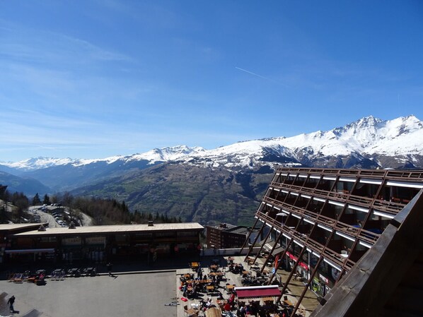 A ski resort with a restaurant on the upper level, offering views of snow-covered mountains.