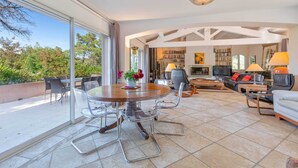 A spacious living area with a round table and chairs, a sofa set, and a television.