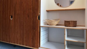 Une pièce avec une armoire en bois, un miroir et des étagères avec des paniers.