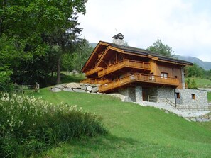 Un chalet en bois avec des fondations en pierre, un balcon et un mur en pierre.