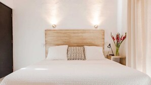Una cama con cabecera de madera, dos lámparas de noche y un jarrón con flores.