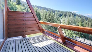 En træterrasse med udsigt til et skovklædt bjerglandskab.