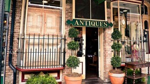 A vintage storefront with a sign reading "ANTIQUE APPARITIONS" and a large window display.