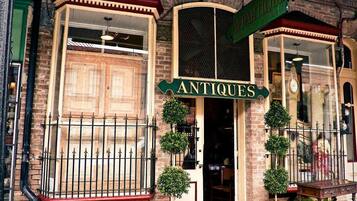 A vintage storefront with a sign reading "ANTIQUE APPARITIONS" and a large window display.