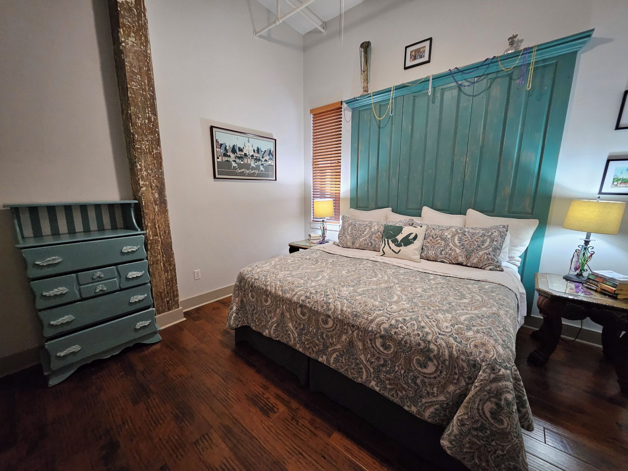 A bedroom with a bed, dresser, and a framed picture on the wall.