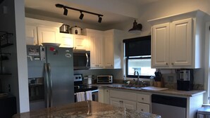 A modern kitchen with white cabinets, stainless steel appliances, a granite countertop, and a window with a view. - Cozy 2 Bed 2 Bath waterfront cottage on beautiful High Rock Lake- fully updated (Lexington)
