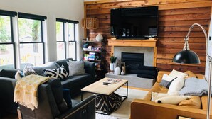 A cozy living room with a fireplace, a television, and a bookshelf. - Cozy 2 Bed 2 Bath waterfront cottage on beautiful High Rock Lake- fully updated (Lexington)