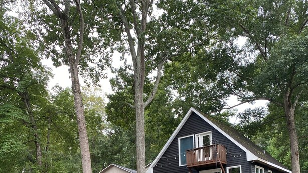 A house with a dock extending into a body of water, surrounded by trees. - Cozy 2 Bed 2 Bath waterfront cottage on beautiful High Rock Lake- fully updated (Lexington)