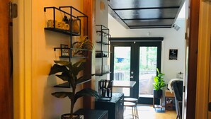 A hallway with wooden flooring, a black cabinet with a plant, and a black shelf with glassware. - Cozy 2 Bed 2 Bath waterfront cottage on beautiful High Rock Lake- fully updated (Lexington)