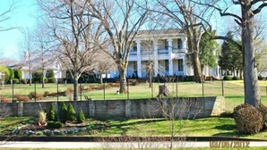 A large, two-story building with a symmetrical facade, surrounded by a well-maintained lawn and a stone wall. - Cabin #1, Kentucky Lake,  Nashville , Birdsong Marina, Paris Landing, Memphis (Camden)