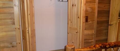 Interior de madera con armario, barandilla de madera y puerta blanca.