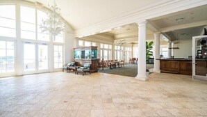 A spacious room with large windows, a chandelier, a fish tank, and a dining area.