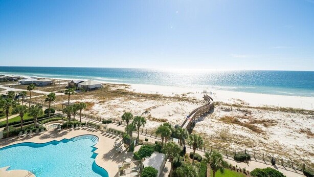 A resort with a swimming pool, beach access, and a view of the ocean.
