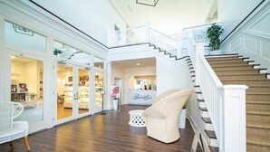 A spacious interior with a wooden floor, white furniture, a staircase, and a sign for 'Beach Club'.