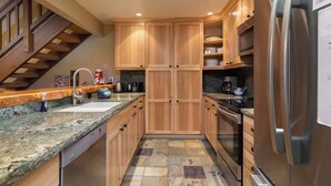 A modern kitchen with wooden cabinets, granite countertops, a stainless steel refrigerator, and a built-in oven. - Walk to Ski & Village, Views Condo, Pool & Spa 315 (Mammoth Lakes)