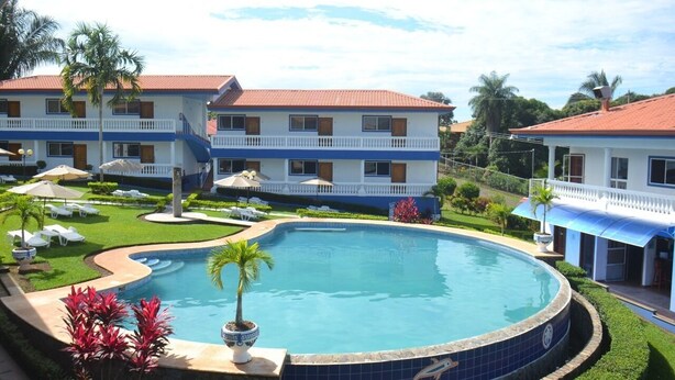 A resort with a swimming pool, multiple-story buildings, and a well-maintained lawn.