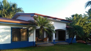 A two-story house with a red roof, blue exterior walls, and a front porch.