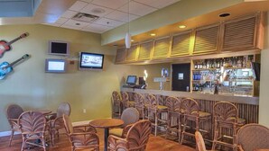 A bar area with wicker chairs, a counter with a variety of bottles, and two televisions mounted on the wall. - Quiet 2 Bedroom Resort Home (Davenport)