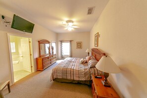 A bedroom with a bed, bedside tables, a dresser, a ceiling fan, and a TV mounted on the wall. - Quiet 2 Bedroom Resort Home (Davenport)