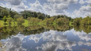 A house with a reflection in a calm body of water, surrounded by trees and greenery. - Quiet 2 Bedroom Resort Home (Davenport)