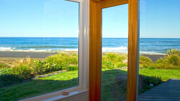 A room with large windows overlooking a beach.