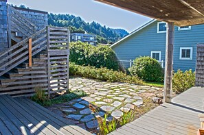 A stone pathway leading to a wooden deck with a staircase. - Agate Point - Ocean / Bay front (Yachats)
