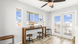 Una cocina con barra de madera, taburetes y un ventilador de techo.