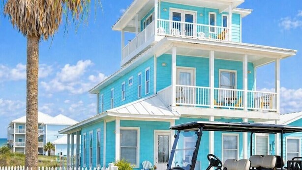 Un edificio de dos pisos con balcón, un carrito de golf y una palmera.