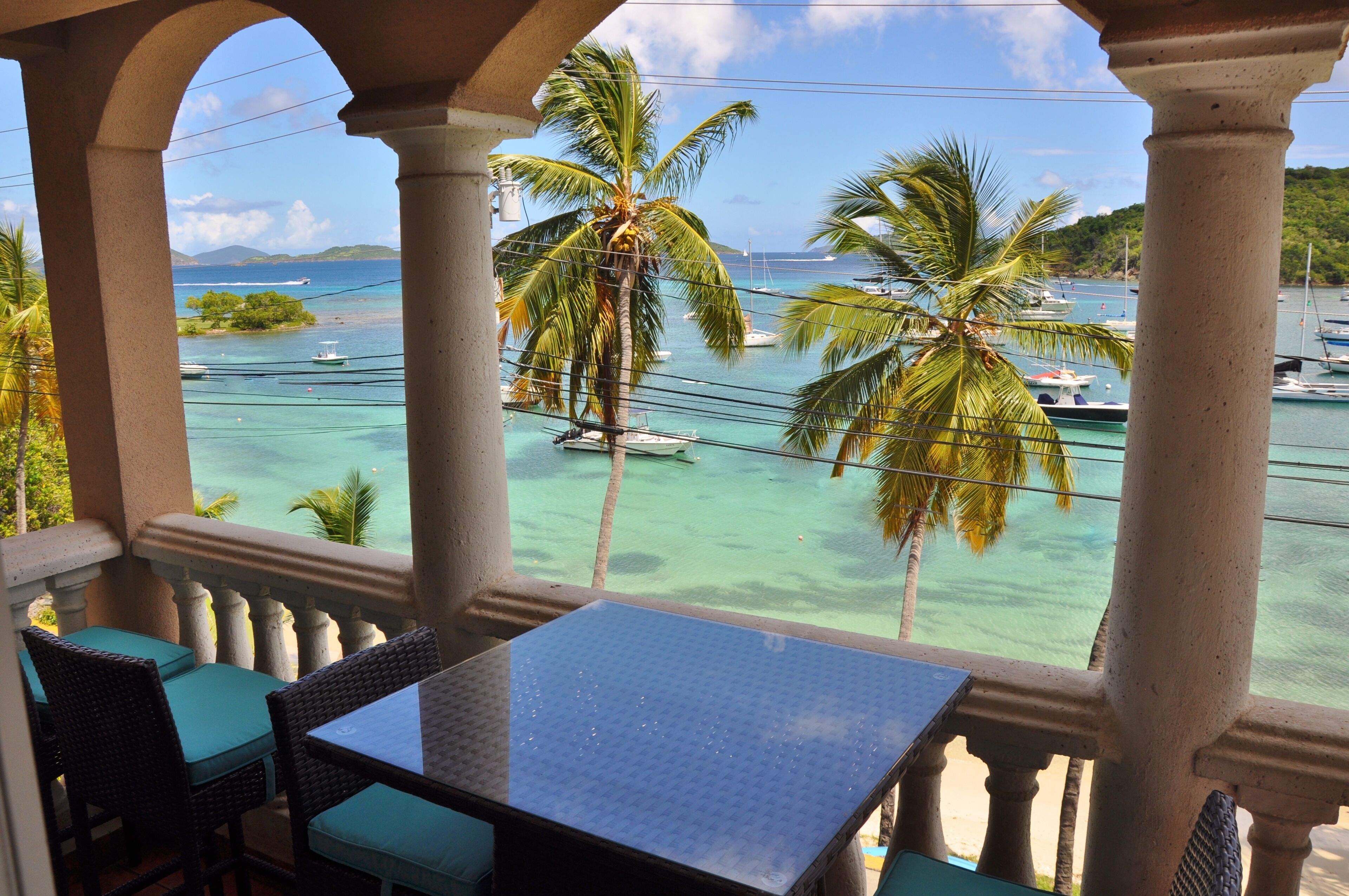 Un balcon avec vue sur une marina, des palmiers et des bateaux.