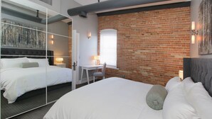 Un dormitorio con una cama grande, un escritorio y una pared de ladrillo.