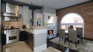 Una cocina moderna con una isla central, horno empotrado y chimenea.