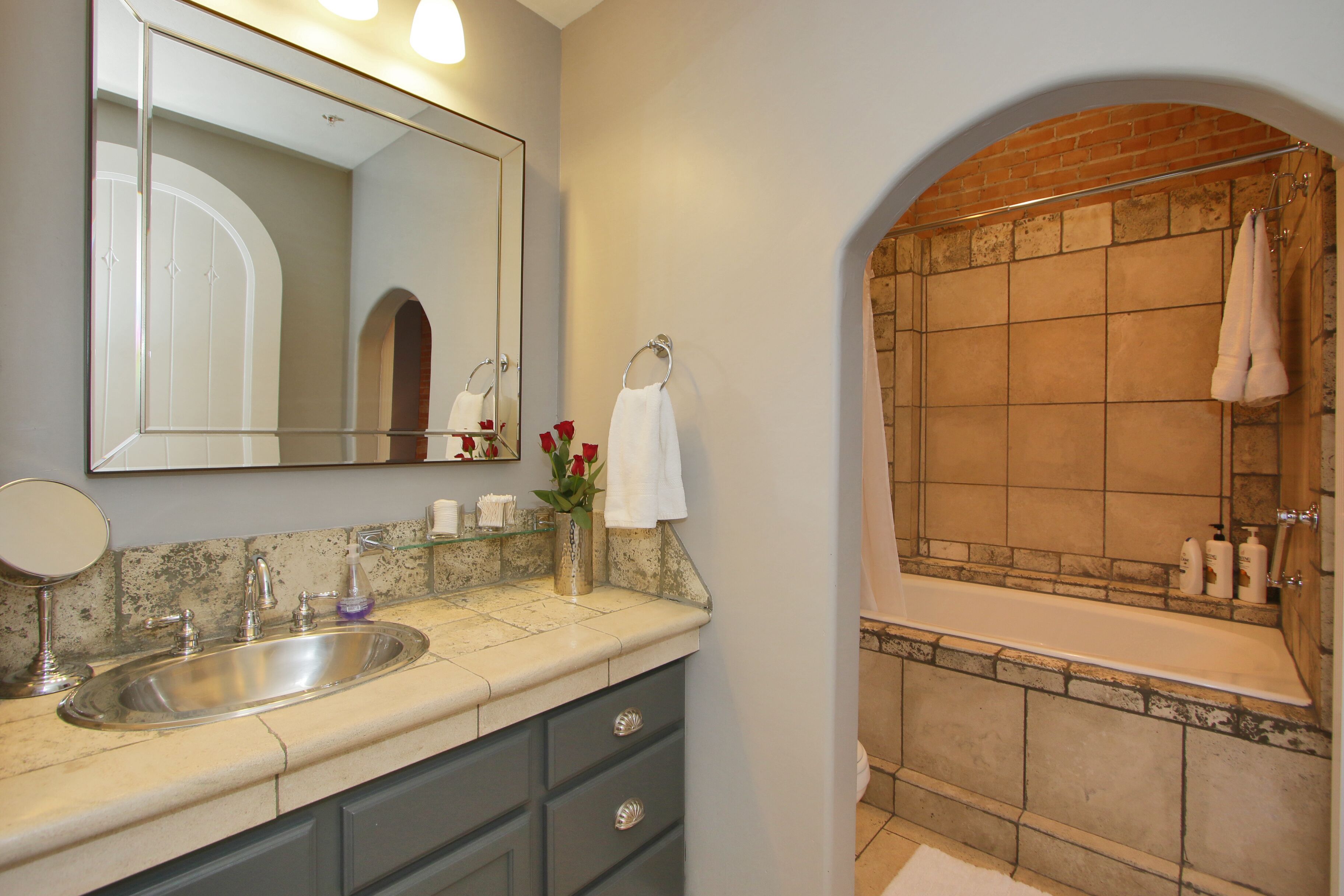 A bathroom with a sink, mirror, and a bathtub with a towel rack.