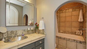 A bathroom with a sink, mirror, and a bathtub with a towel rack.