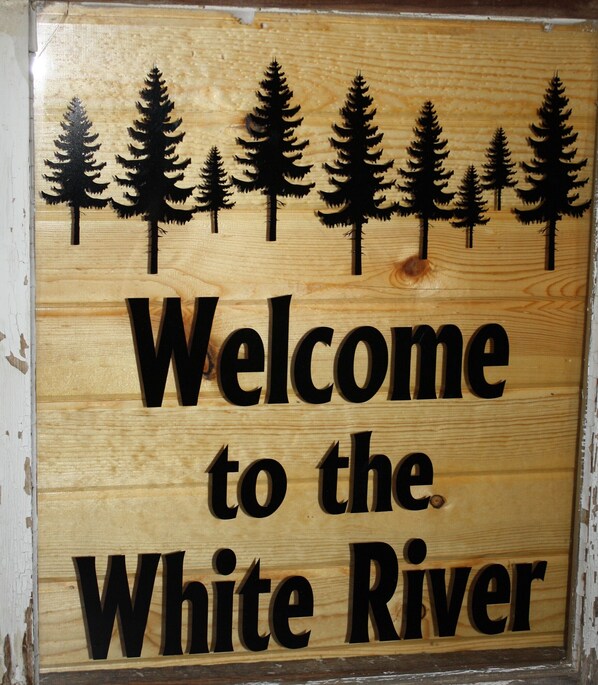 A wooden sign with the text "Welcome to the White River" and silhouettes of trees.