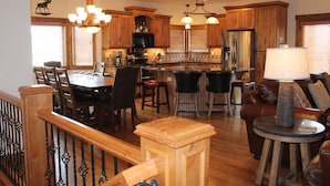 A spacious kitchen with wooden cabinets, a central island, and a dining area with chairs.