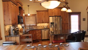 A kitchen with wooden cabinets, stainless steel appliances, and a dining area with a table and chairs.