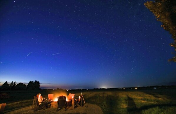 Relax by the fire pit in a serene, open space with a clear view of the starry sky.