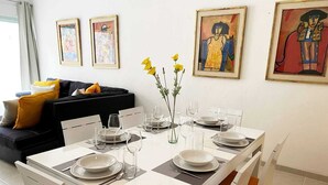 A dining area with a white table set for four, surrounded by chairs, with artwork on the walls. - Walk to Beach, Private rooftop, Pool, Parking, M3 (Playa del Carmen)