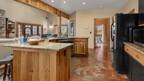 A spacious kitchen with a wooden island, built-in oven, and black refrigerator. - Hot tub, Fireplaces, Game room, Rustic elegance, Private, 10 miles to AVL. (Fairview)