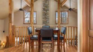 A dining area with a stone fireplace, wooden beams, and a view of the outdoors. - Hot tub, Fireplaces, Game room, Rustic elegance, Private, 10 miles to AVL. (Fairview)
