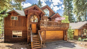 Een houten chalet met een balkon, een garage en een trap naar de ingang.