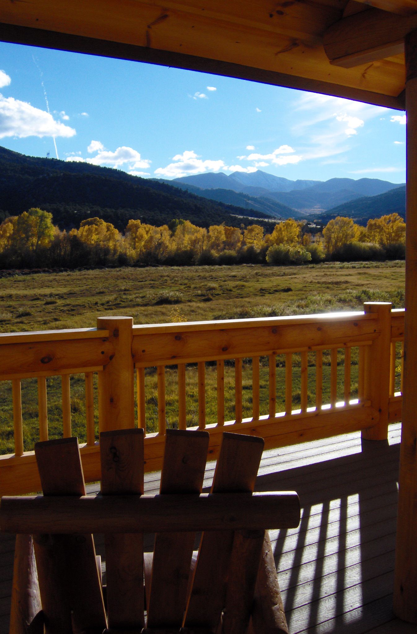 A wooden deck with a view of a valley and mountains.