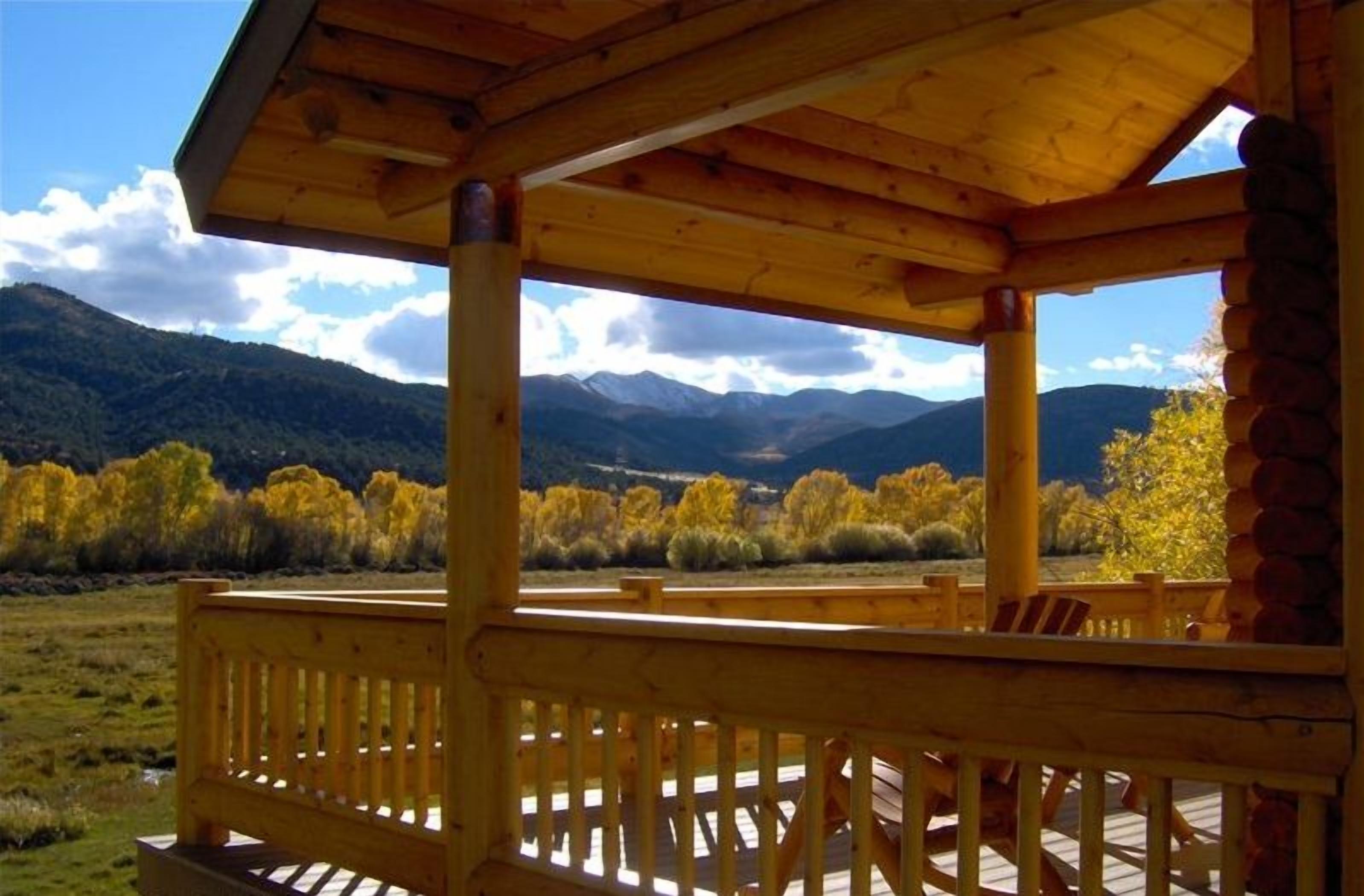 A wooden deck with a view of mountains and autumn foliage.