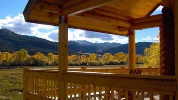A wooden deck with a view of mountains and autumn foliage.