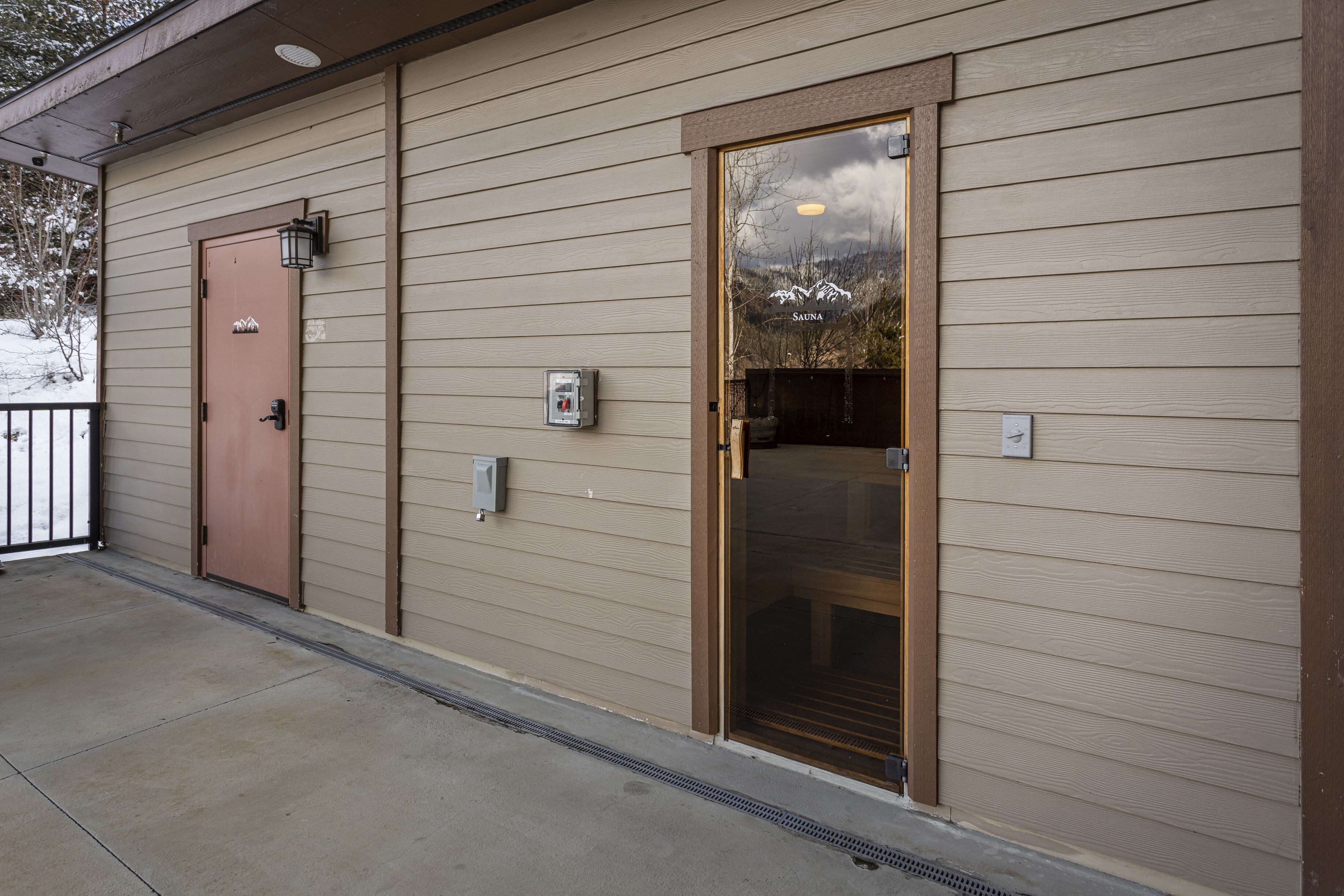 A building with a beige exterior, a brown door, and a large glass window.