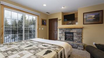 Relax in a serene bedroom with a large bed, cozy seating area, and stone fireplace.