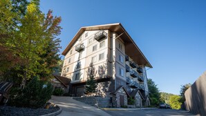 Un immeuble à plusieurs étages doté de balcons, d’une façade en pierre et d’un espace de stationnement.