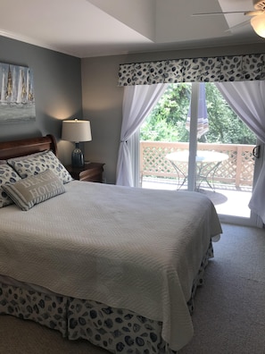 Relax in this serene bedroom with a large bed, bedside table, and balcony with a view.