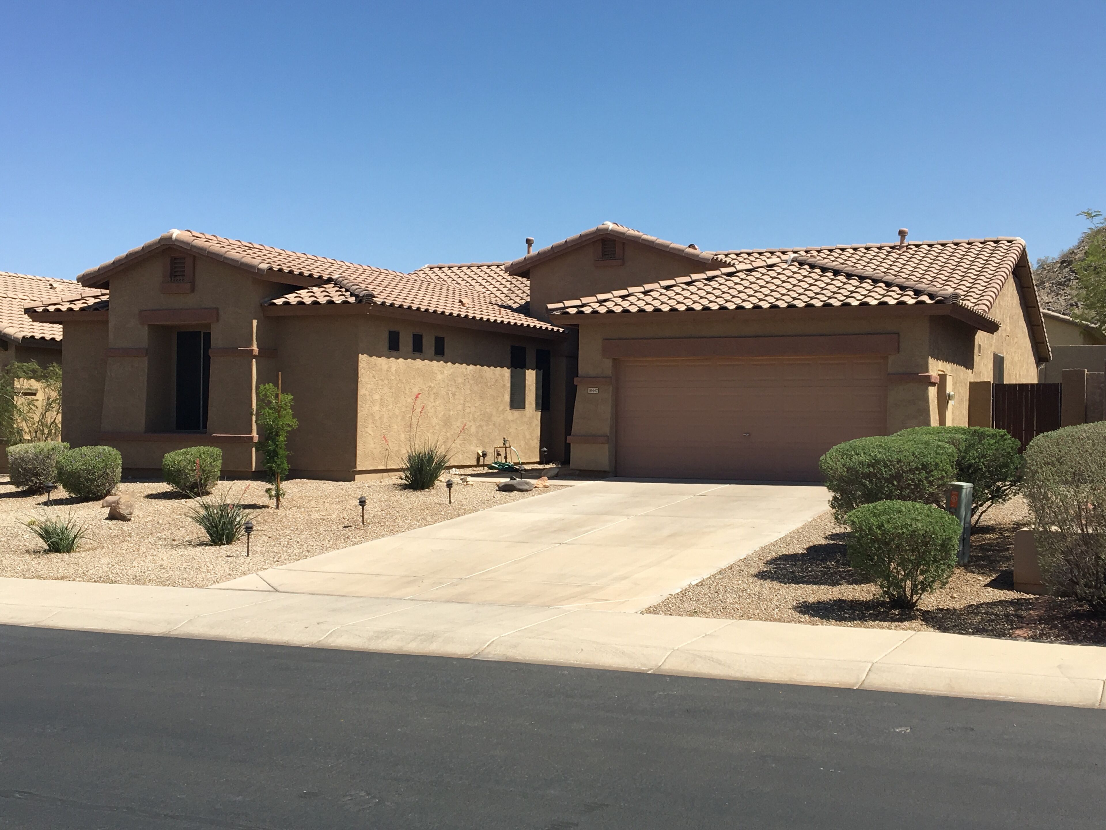A two-story house with a tiled roof, a garage, and a driveway.